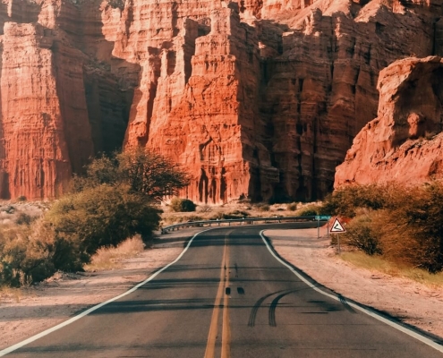 Road in Argentina with red rock mountains in the back
