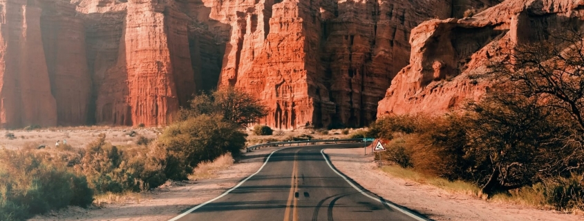 Road in Argentina with red rock mountains in the back