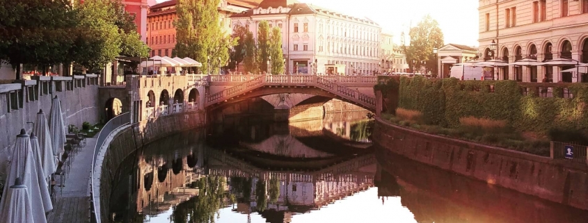 River in Slovenia, with sun reflecting in the water and old nice buildings on the sides